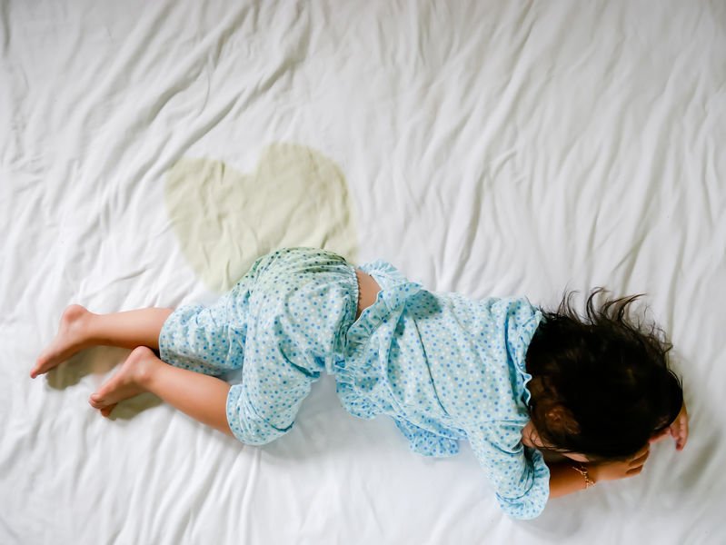 Jente liggende på tissevåt seng - plaget med sengevæting